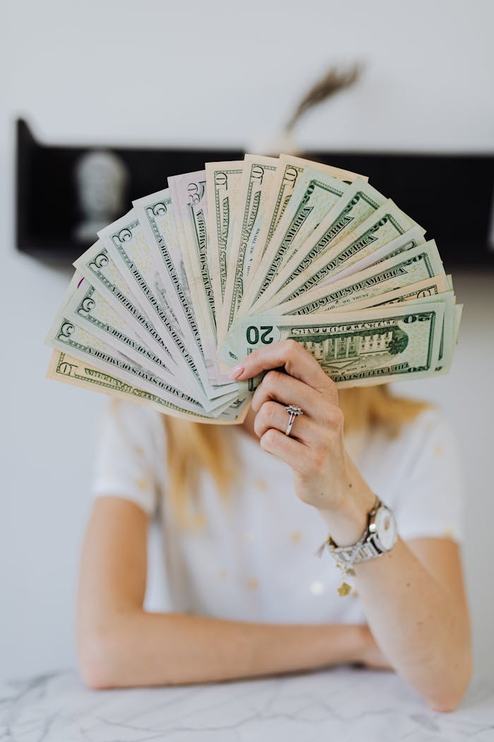 portfolio-03 A person holding a fan of US dollar bills, symbolizing wealth and financial success.