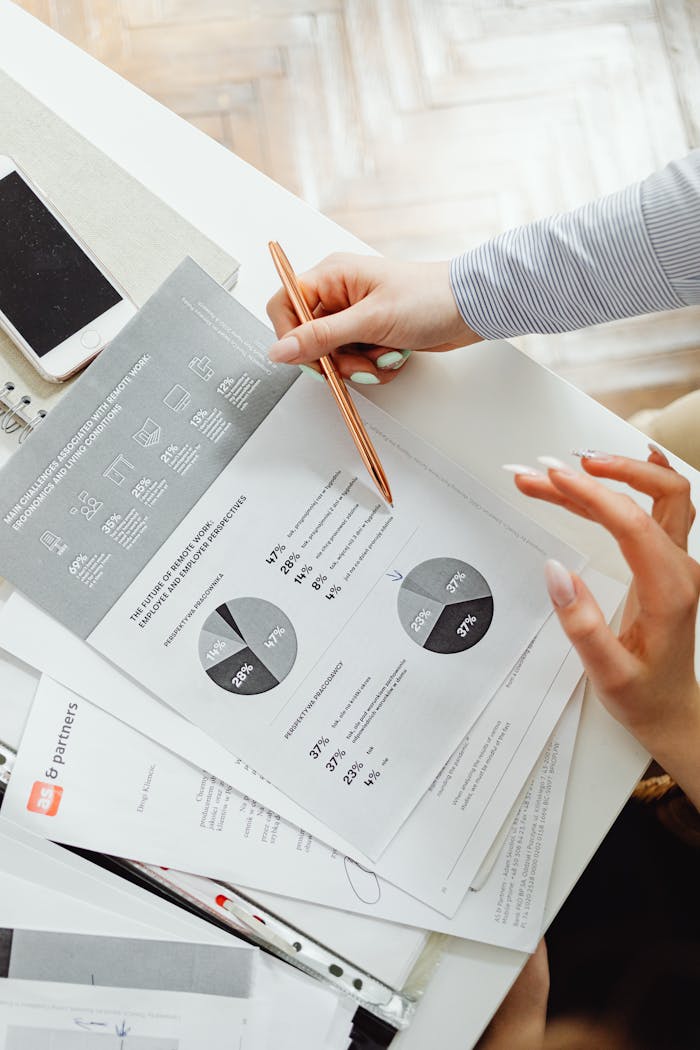 stats-img Close-up of businesswoman analyzing financial reports using pie charts in an office setting.