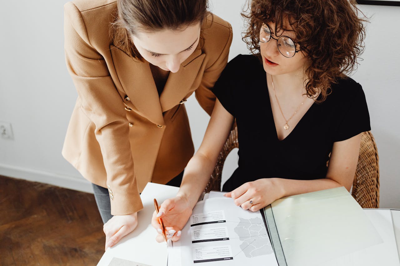 why-choose-us Two women discussing and analyzing business paperwork together in an office setting.