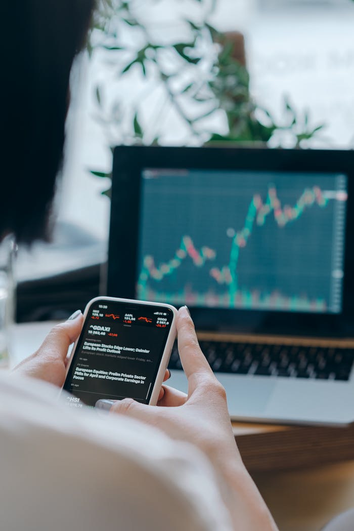 portfolio-05 Person using smartphone for stock market analysis at home office.